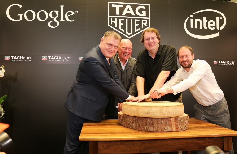 Representatives from Google, Tag Heuer and Intel cut into a large cheese to celebrate their partnership