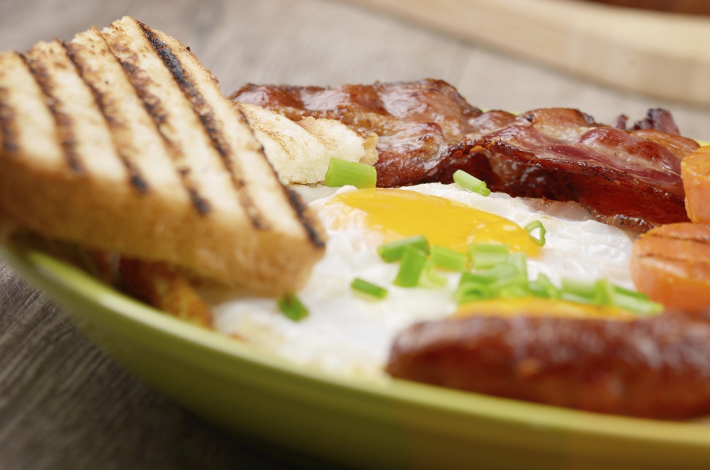 Fried eggs with bacon sausages and greens