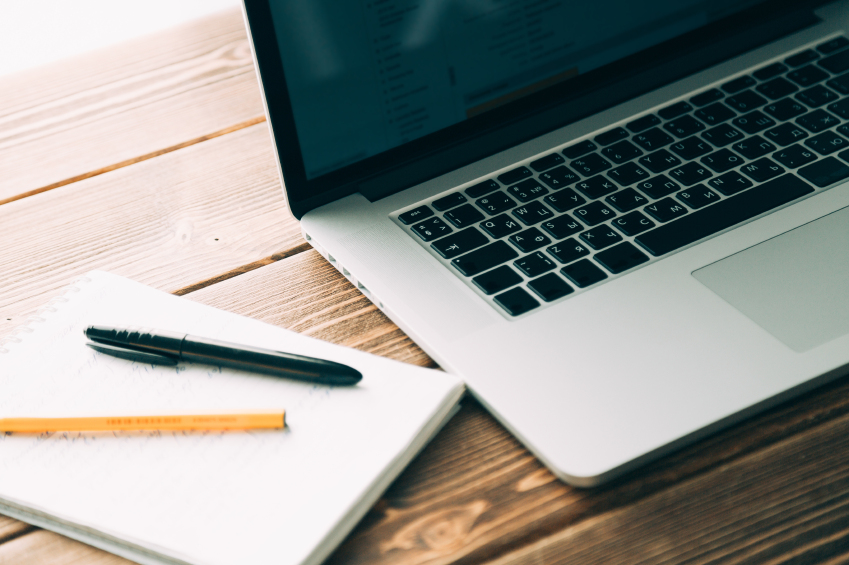 Workplace with open laptop on modern wooden desk, angled notebook on table in home interior, filtered image, soft focus