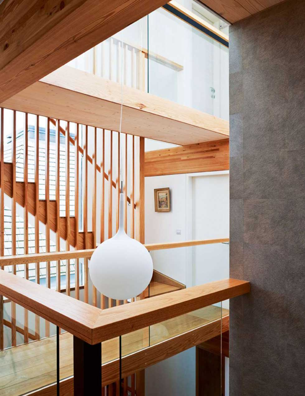 The striking oak staircase was crafted by Cambridge Joinery, with a tall louvred baluster running through all three storeys — creating an internal brise soleil