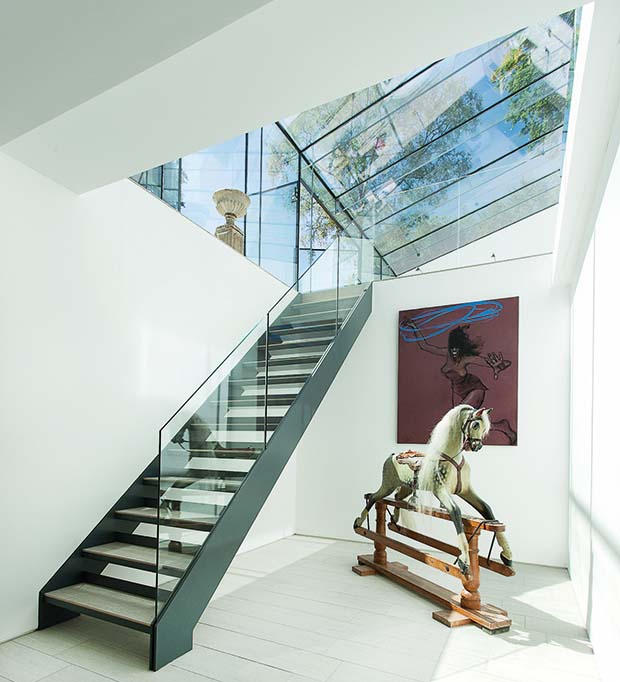 a frameless glass extension and staircase with glass balustrade and rocking horse