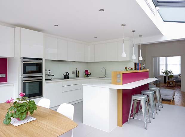 A side extension kitchen on a small terraced home with red feature low wall