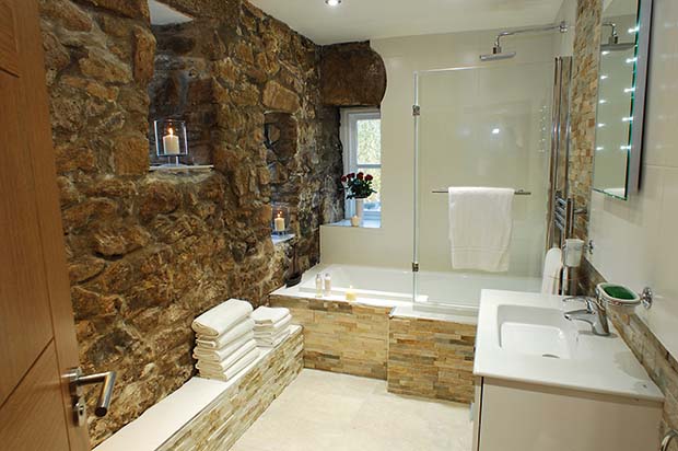 Exposed stone walls in a luxury bathroom in a barn conversion holiday let in Cornwall