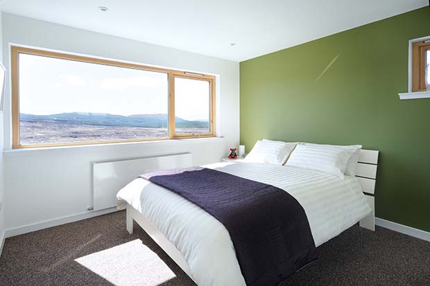 The bedroom of White Tail Croft with green wall and picture window