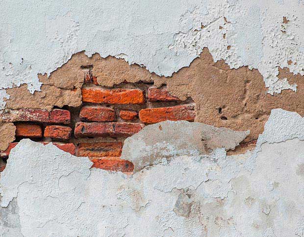 blown render on a white wall with exposed brickwork