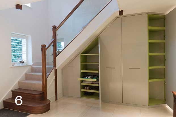 Understairs cupboards under a stair with wooden newel posts and banister and glass balustrade