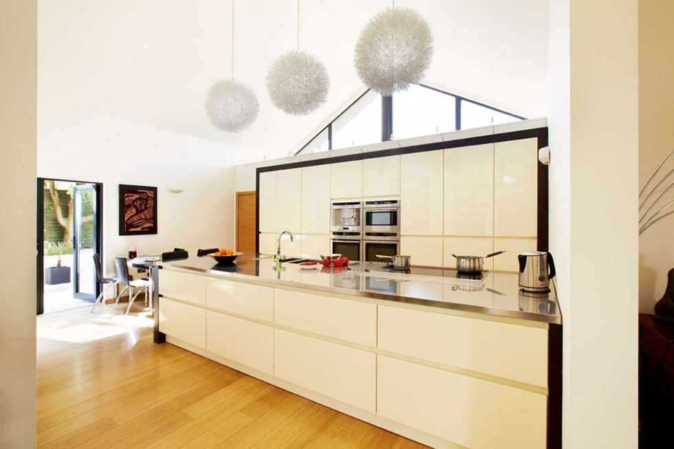 This simple, open plan kitchen/dining area occupies one end of the living space with tall units and a large island unit. It opens into the courtyard garden. View Project →