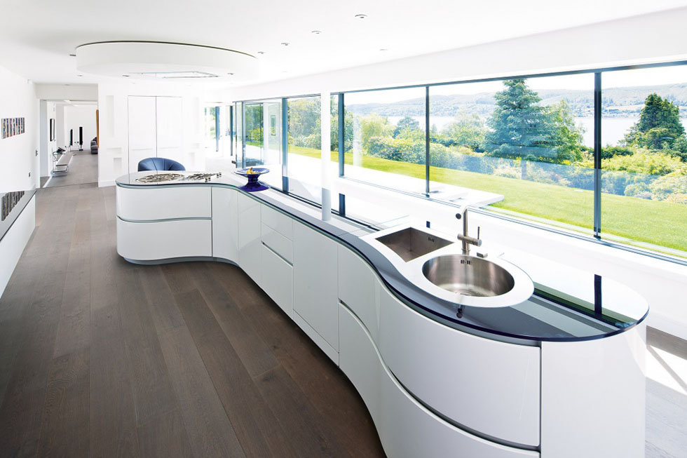 The high-spec Italian curvilinear kitchen island, with integrated appliances has been angled to face the glazed wall and dramatic views beyond. View Project →