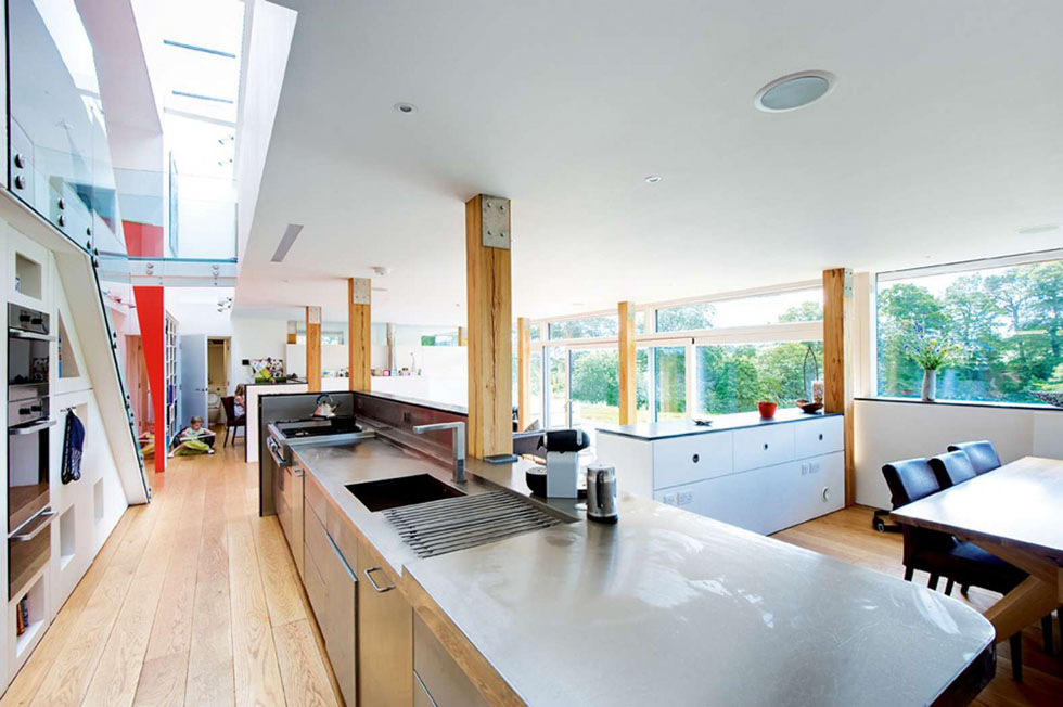 A clean, industrial effect is created by leaving the structural beams exposed, contrasting with the glazed balustrade and metal kitchen island. View Project →