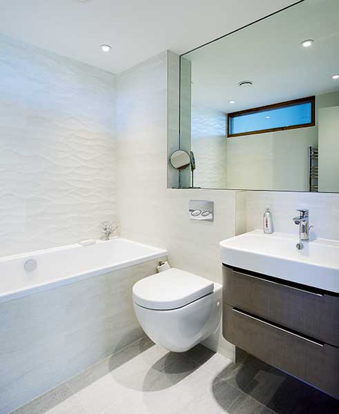 contemporary bathroom with bath and dark wood vanity unit