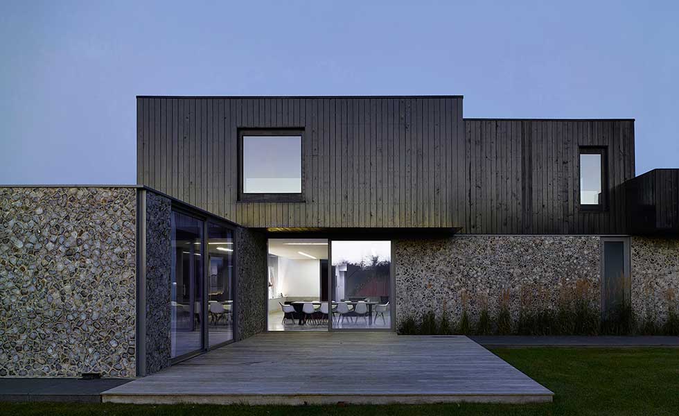 contemporary boxy home with wooden panel and stone finish as well as sliding glass doors