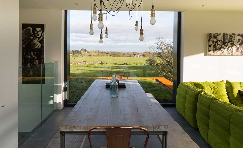 dining room with large glass window overlooking countryside, with exposed lightbulb fiixture