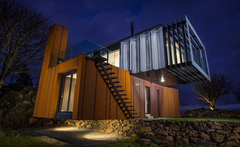 night shot of shipping container home with over extending balcony