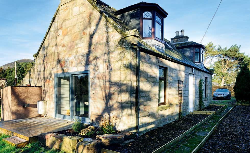 stone cottage with light blue french glass windows and dark wood windows
