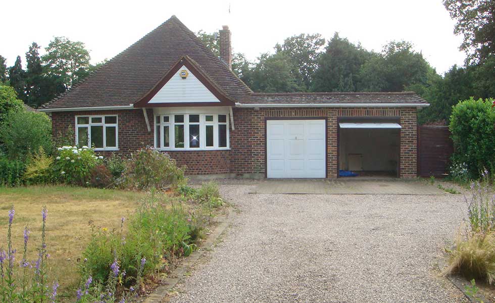 bungalow with steep pitched roof and double garage to the side