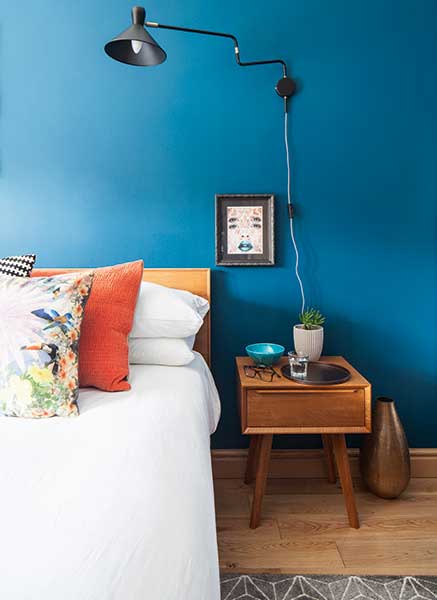 retro style bedside table and bed in blue bedroom