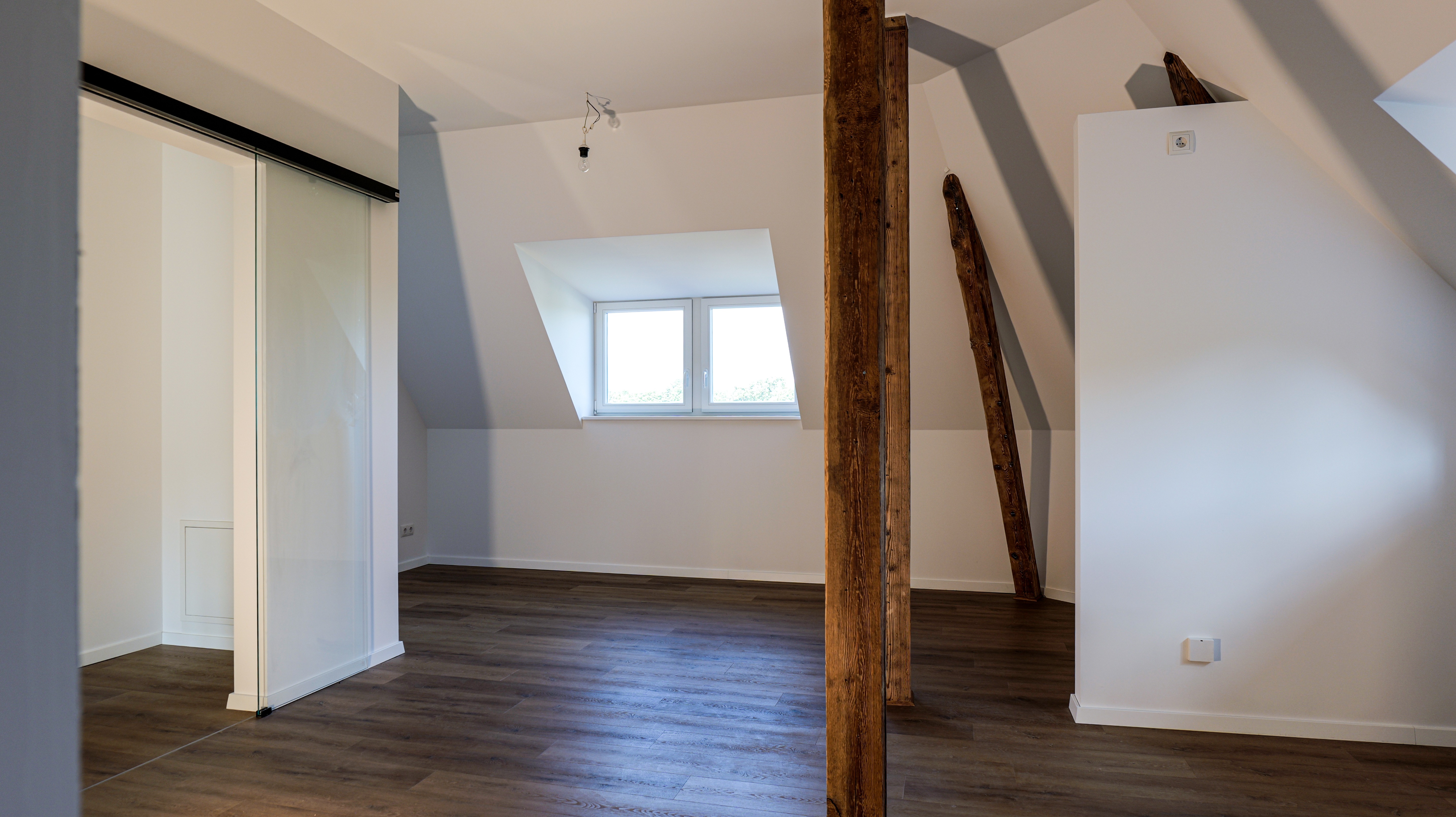 Charme trifft Funktion: Die großzügige Wohnküche begeistert mit sichtbaren Holzbalken und eleganter Glasschiebetür.
