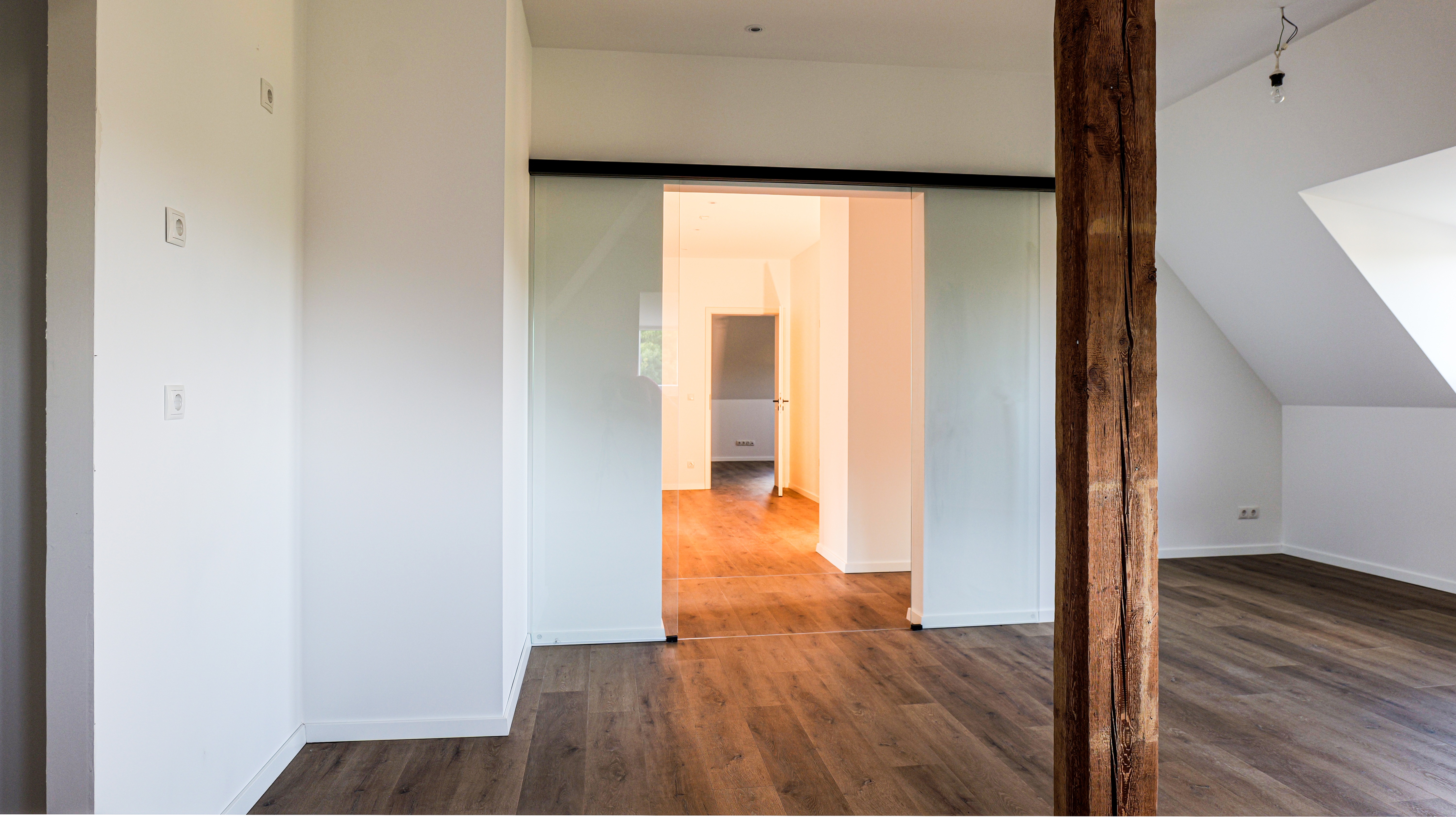 Charme trifft Funktion: Die großzügige Wohnküche begeistert mit sichtbaren Holzbalken und eleganter Glasschiebetür.