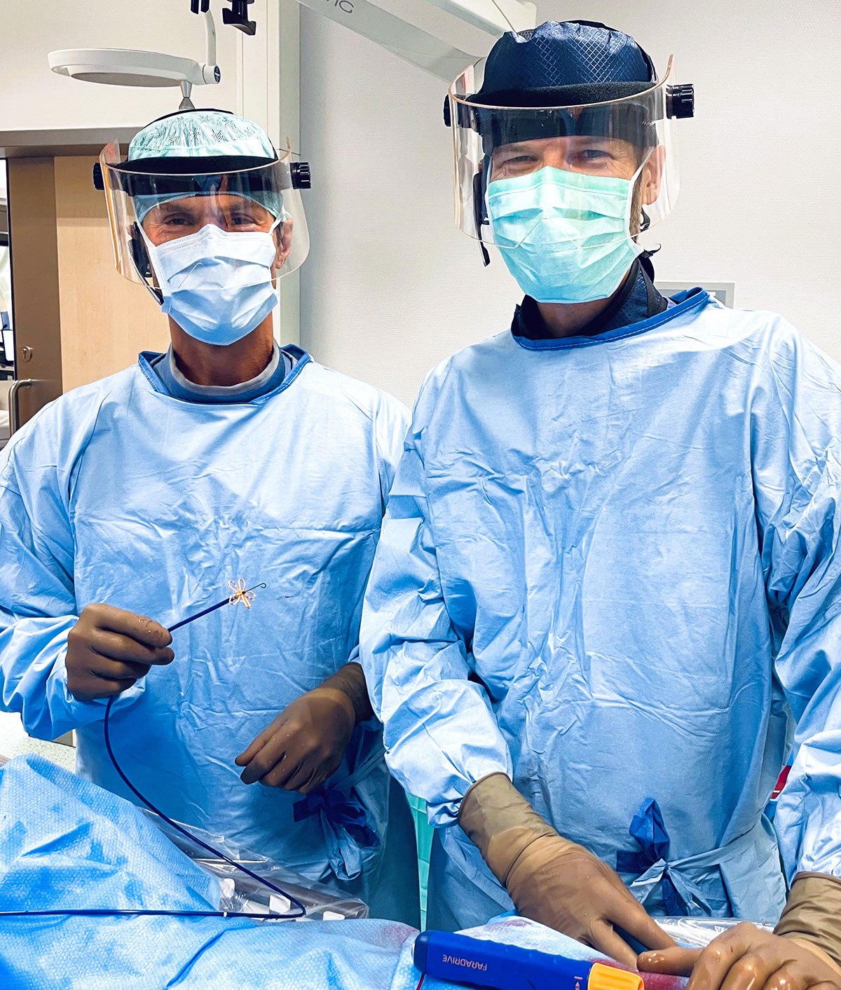 Zwei Ärzte in OP-Kleidung und mit Mundschutz, einer von ihnen hält ein Instrument mit blütenförmigem Aufsatz in der Hand