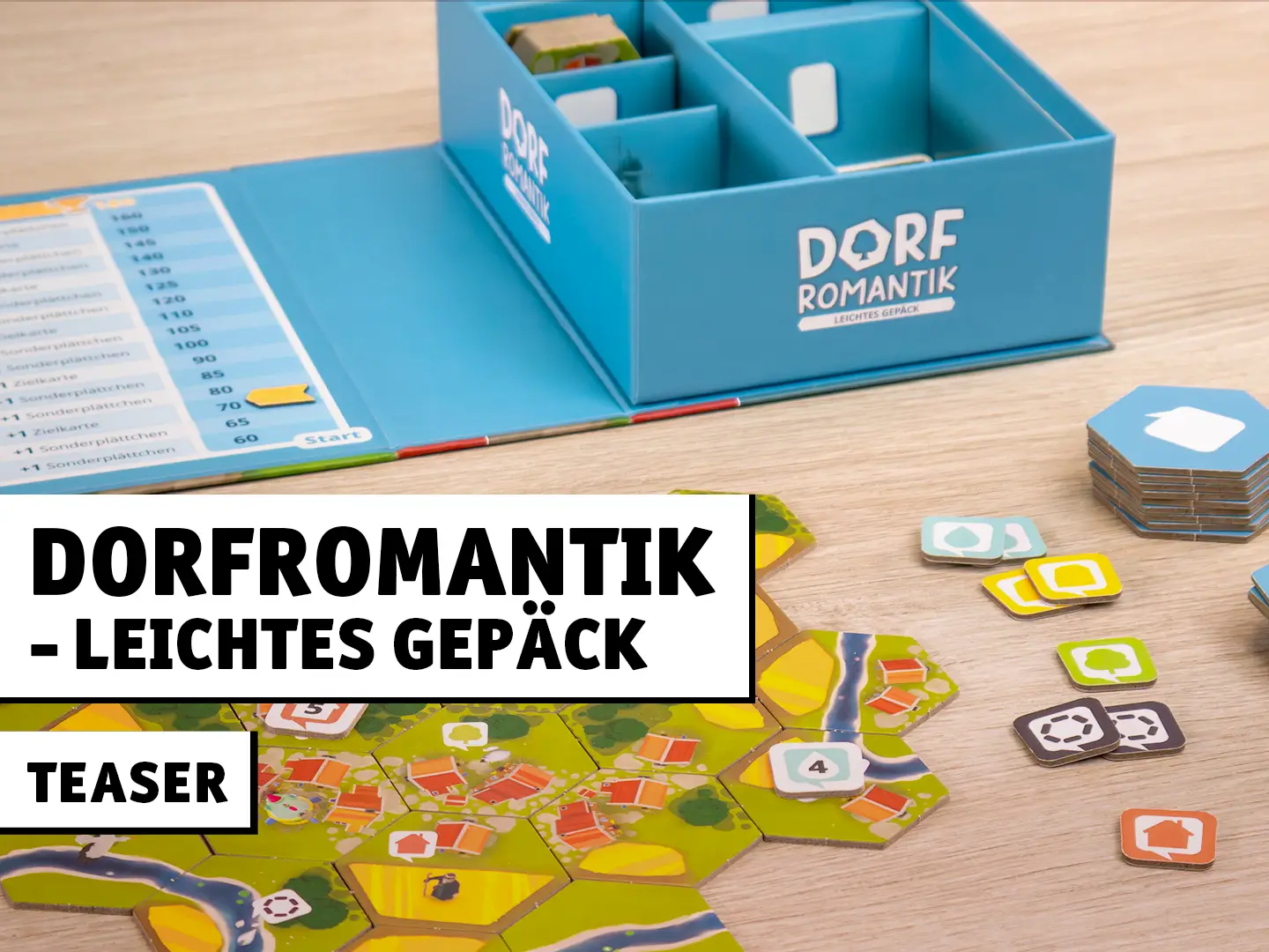 Dorfromantik – Leichtes Gepäck Brettspiel mit Spielbox, Landschaftsplättchen und Markern auf einem Tisch aufgebaut.