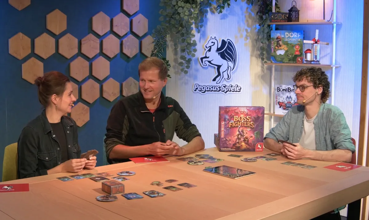 Drei Personen sitzen am Tisch und spielen das Brettspiel Boss Fighters QR