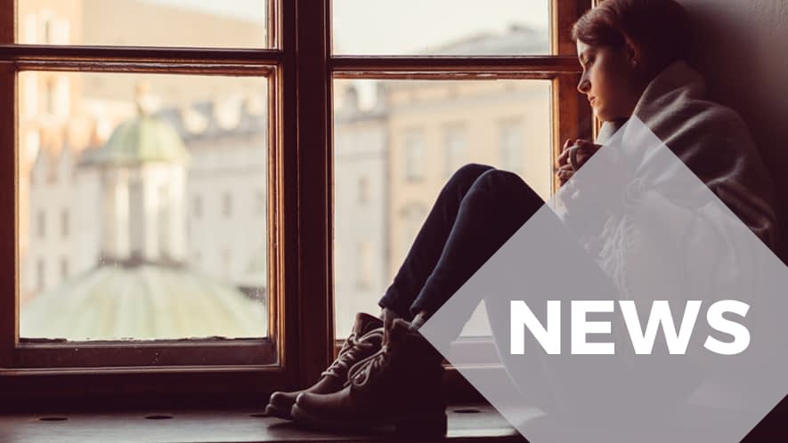 Junge Frau sitzt mit Teetasse auf Fensterbank 