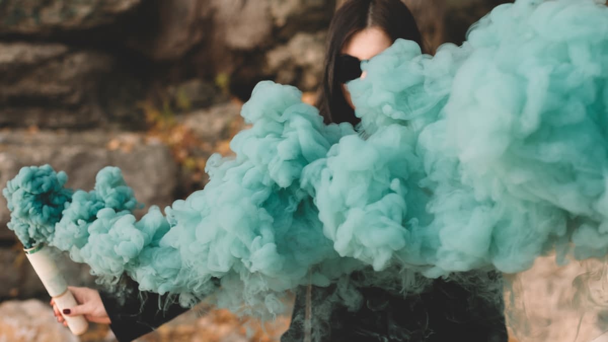 Frau hinter farbiger Rauchwolke