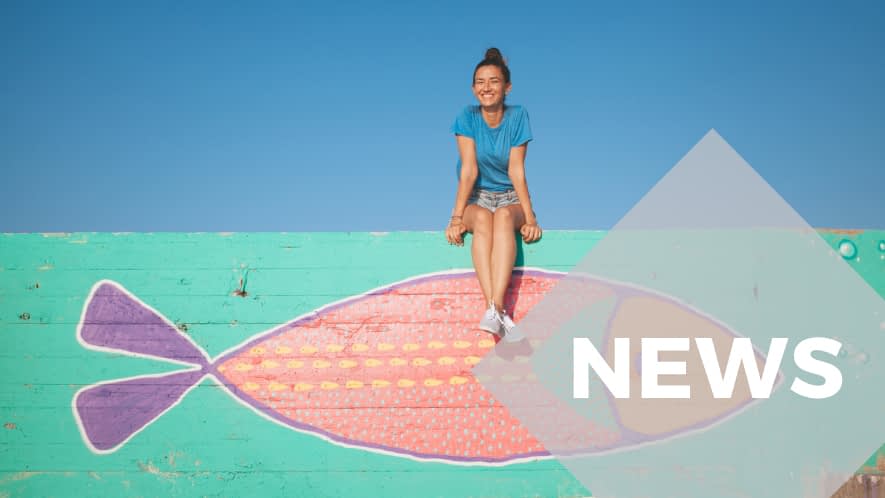 Mädchen sitzt auf einer Mauer mit Fisch-Graffiti