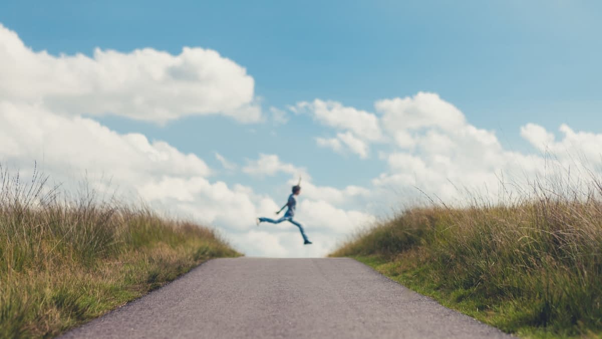 Teenager springt über einen Weg in den Dünen