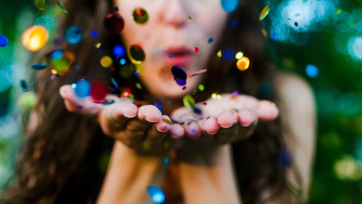 Frau, die Konfetti von Händen pustet