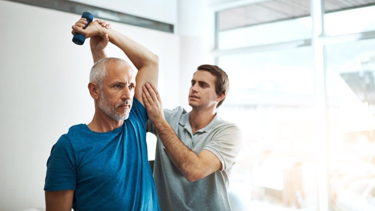 Mann dehnt den Arm eines anderen Mannes Mann dehnt den Arm eines anderen Mannes