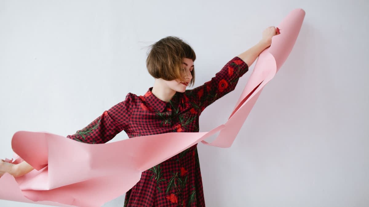 Frau zerreißt rosa Papier