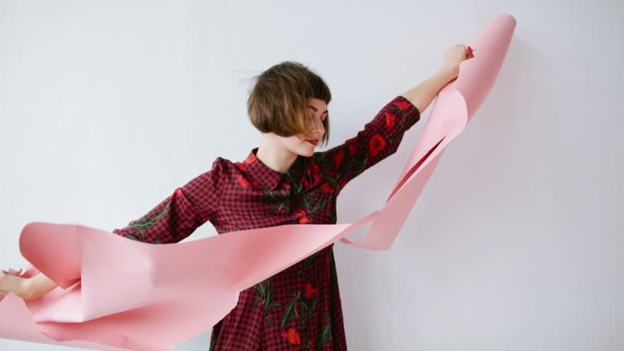 Frau zerreißt rosa Papier