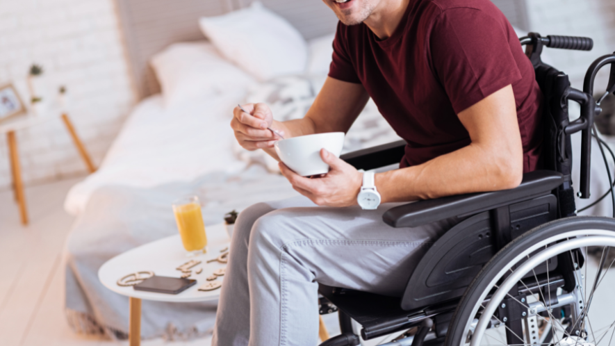 Mann im Rollstuhl frühstückt