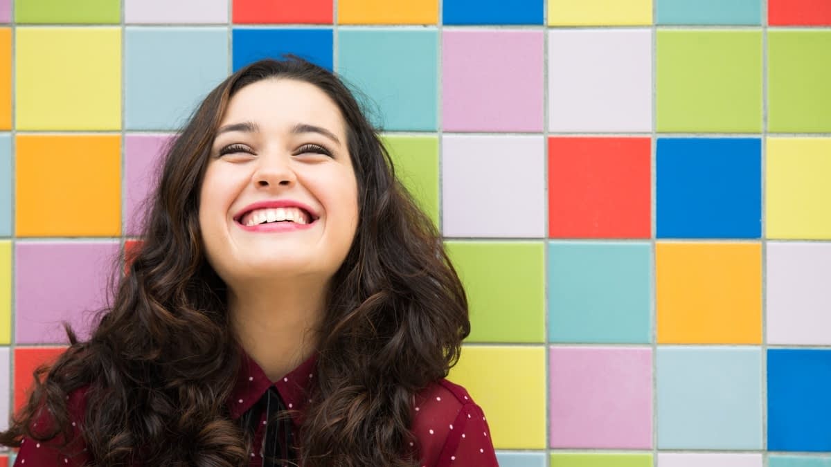 Lachende Frau vor bunter Wand