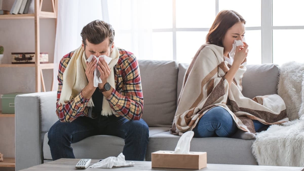 Krankes Pärchen auf einem Sofa die Nase putzend