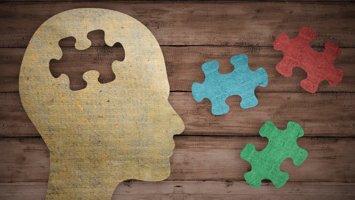 Kopfprofil aus Papier auf Holzuntergrund mit Puzzleteilen