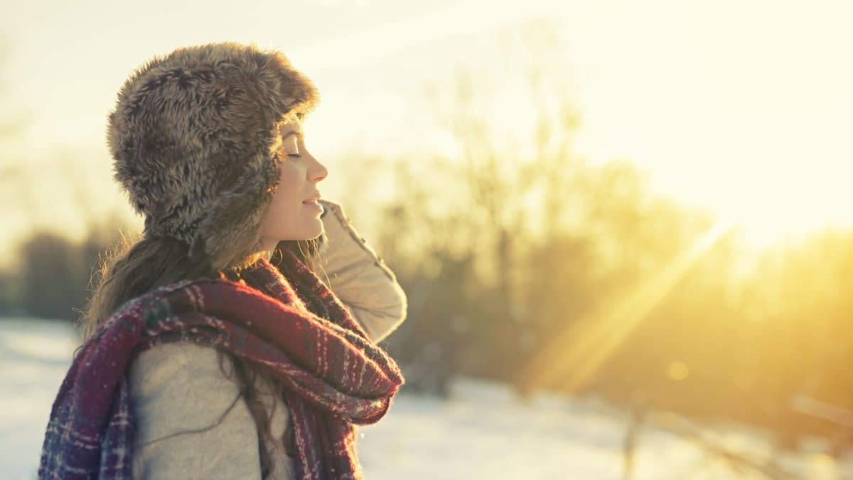 Frau vor Winterlandschaft mit Sonne Frau vor Winterlandschaft mit Sonne