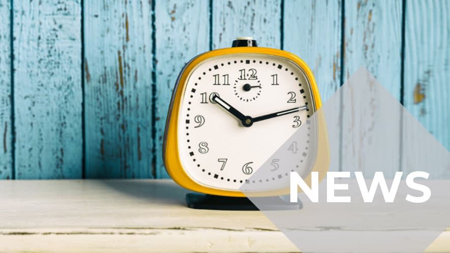 Gelber Wecker vor blauer Holzwand