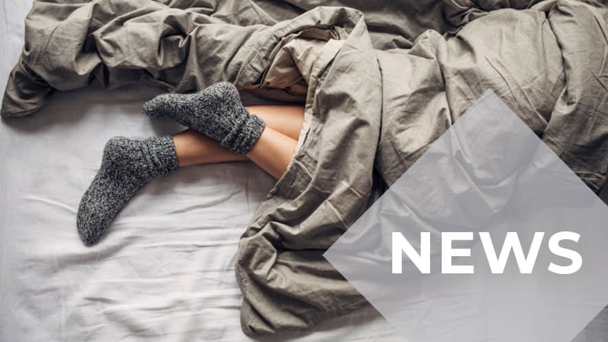 Füße mit Socken gucken unter Bettdecke hervor