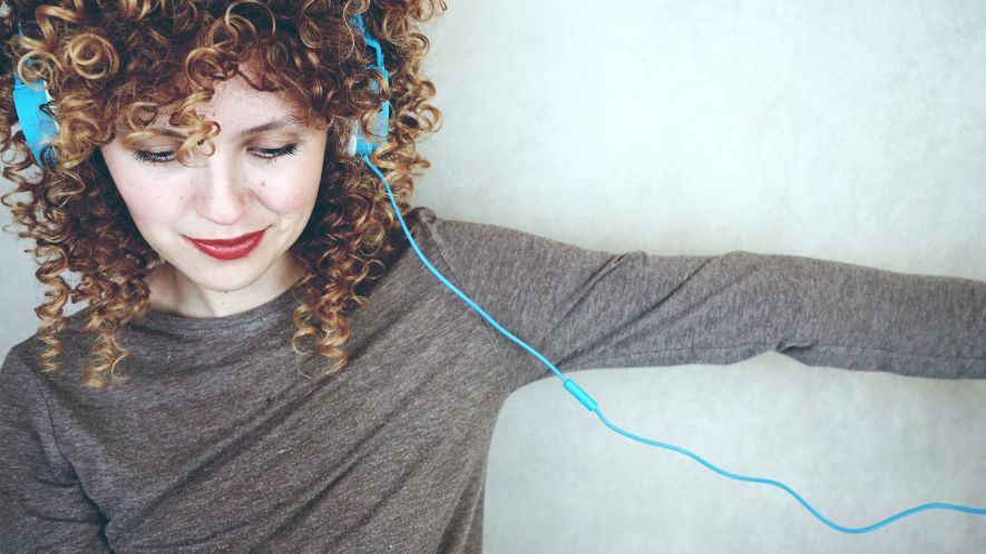 Lächelnde Frau mit Locken und blauem Kopfhörer