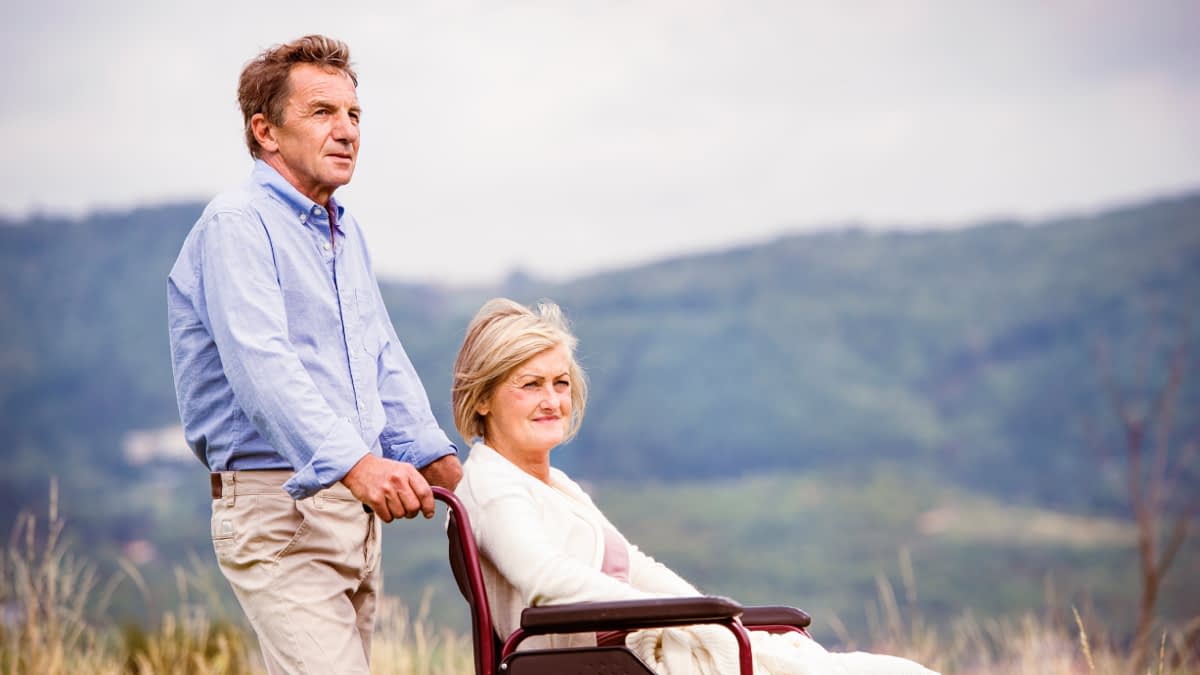 Mann schiebt Frau im Rollstuhl