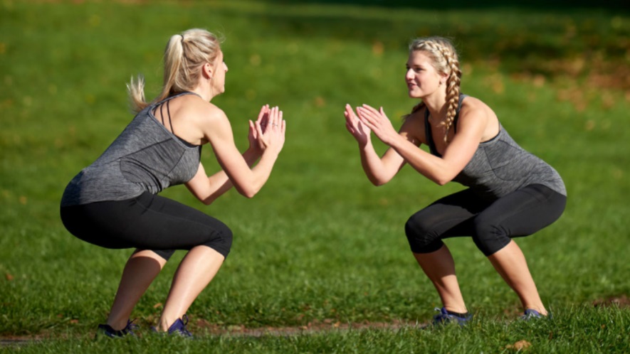 Zwei Frauen machen Kniebeugen