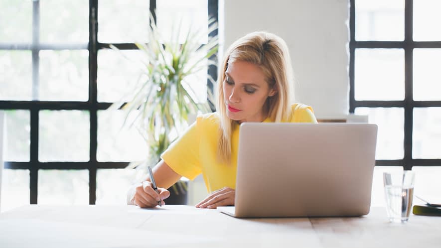 Frau vor dem Laptop bearbeitet Unterlagen
