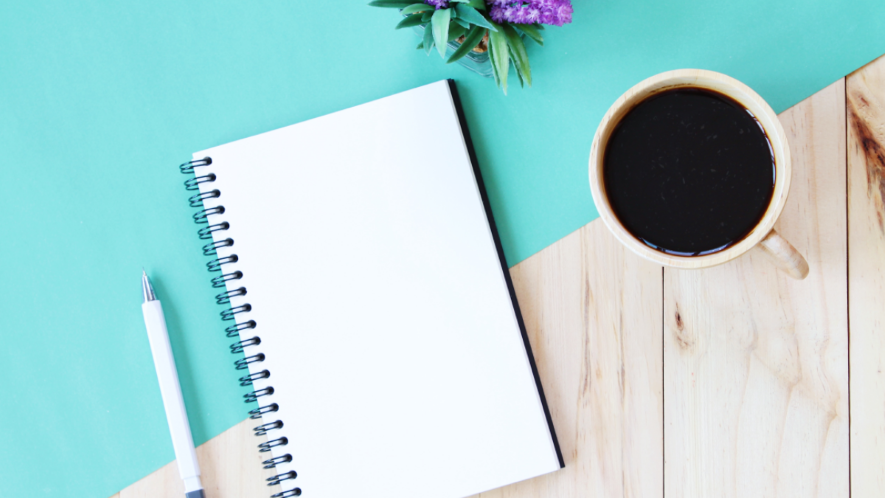 Schreibblock, Stift und eine Tasse Kaffee