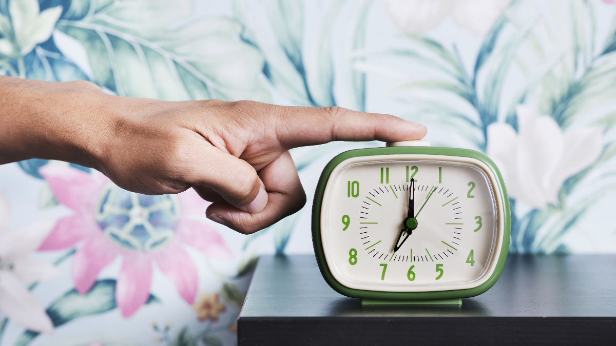 Mann stellt grünen Wecker aus Mann stellt grünen Wecker aus