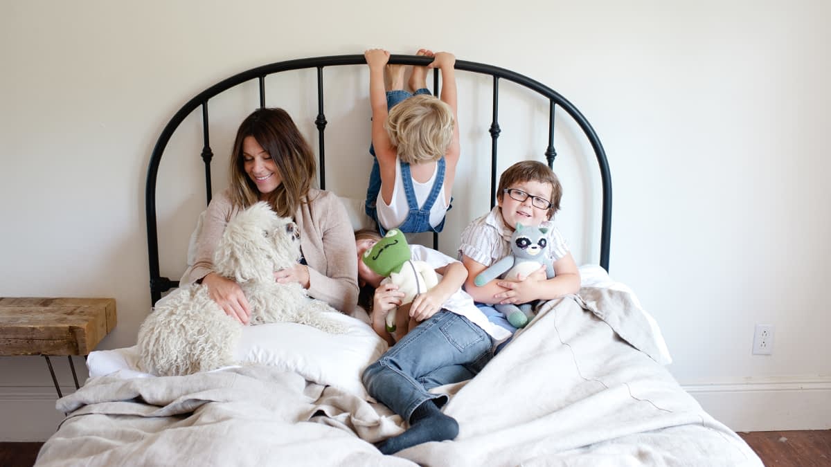 Mutter mit drei Kindern und Hund im Bett