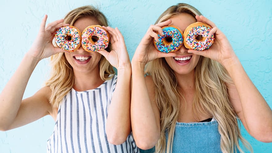 Zwei Frauen albern mit Donuts herum