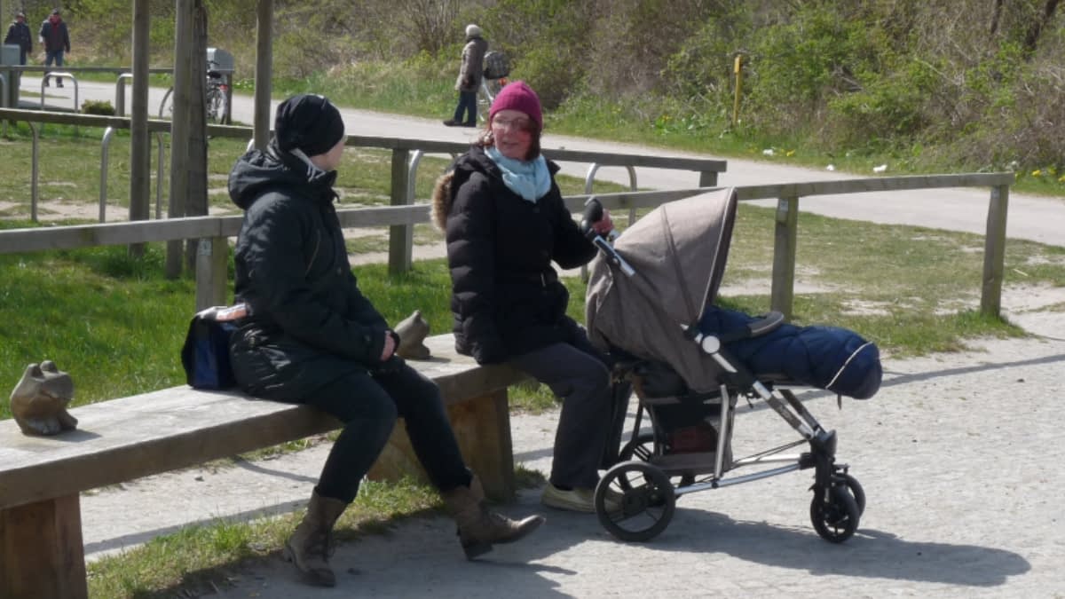 Heike mit Kinderwagen auf einer Bank