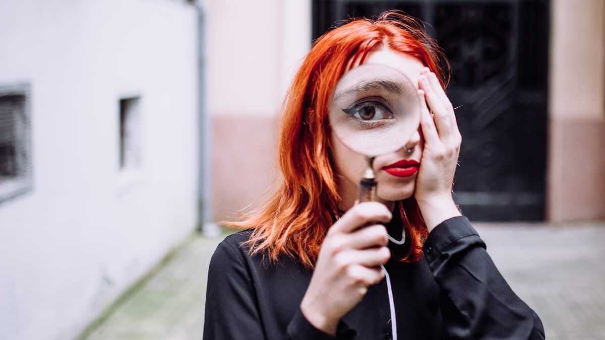 Frau schaut durch Lupe